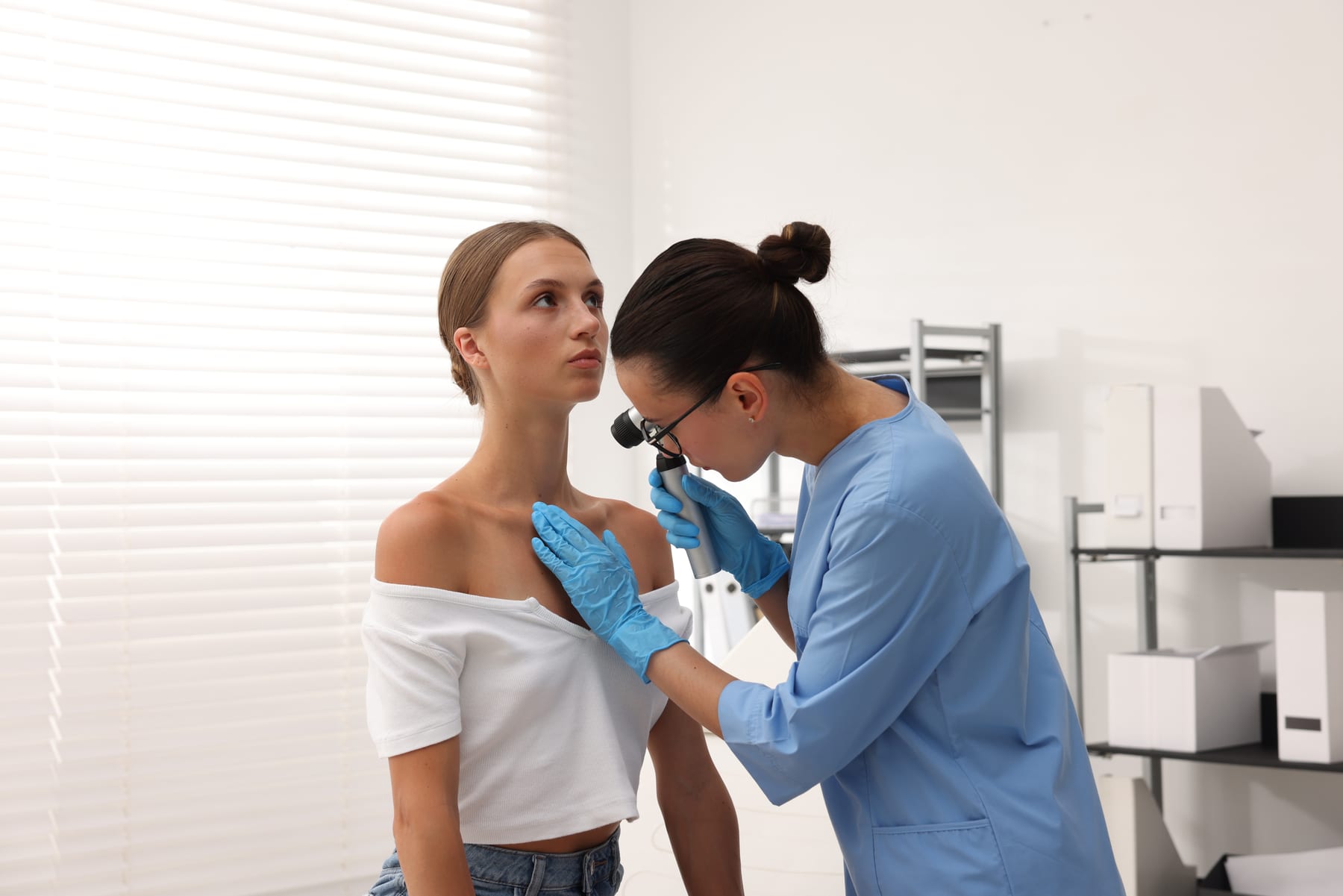 A dermatologist examining a patient's mole with a dermatoscope